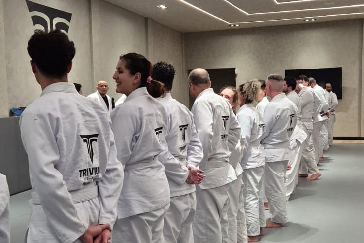 Turma adulta de jiu-jitsu da Trivium perfilada no tatame no início da aula