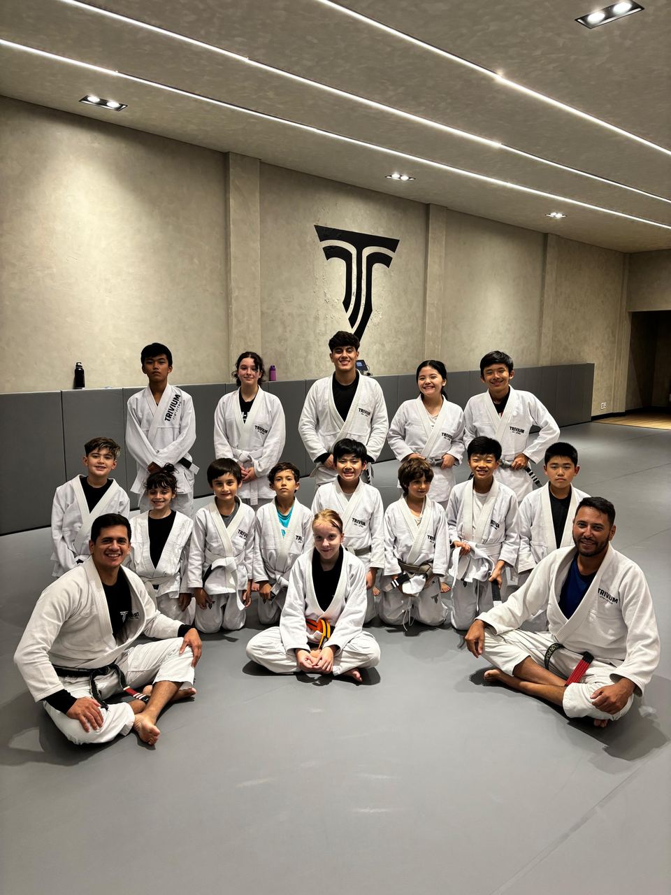 Turma infantil da Trivium reunida no tatame com os professores faixa preta